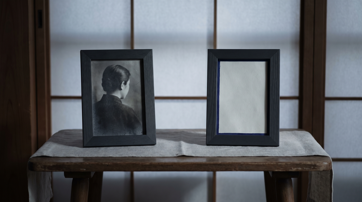 A child's bedroom in morning light: a photograph of a real child beside a blank sheet where another photograph should be — the gap where presence was expected but not found.