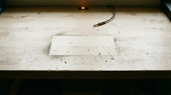 An empty workspace where a tool once sat — the clean absence left when something functional is withdrawn before its users are finished with it.