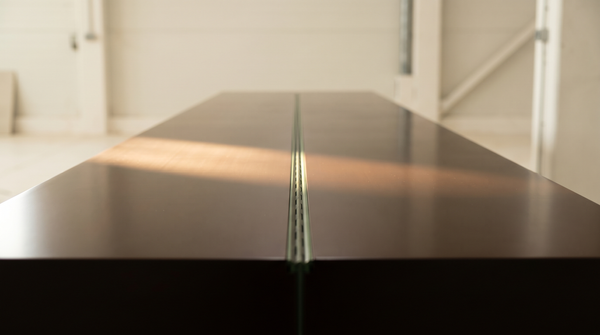 A lacquered surface with a structural seam visible only at an oblique angle — the polished exterior of a bundled IPO narrative and the joint underneath it.